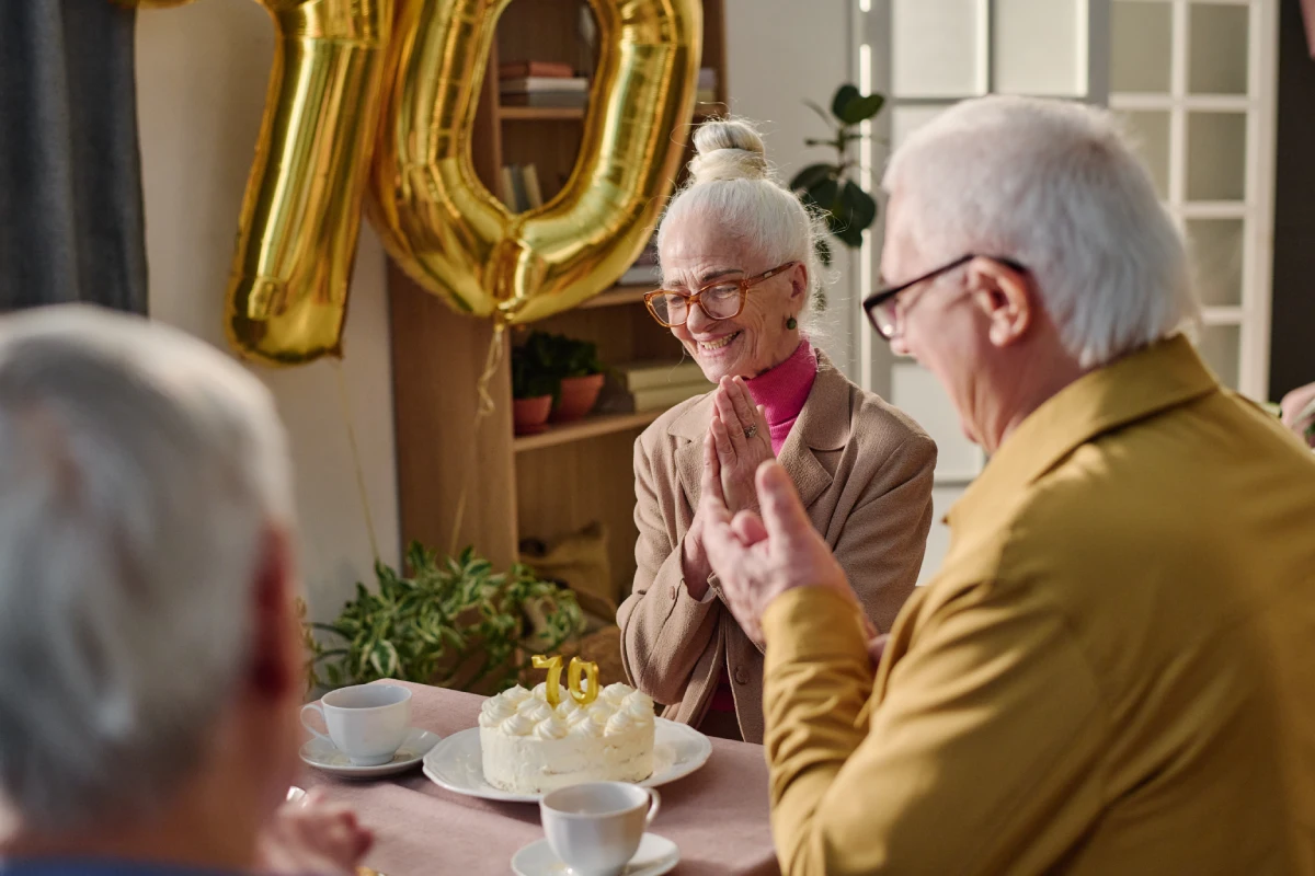 Dona gran feliç celebrant el seu 70è aniversari amb amics i un pastís.