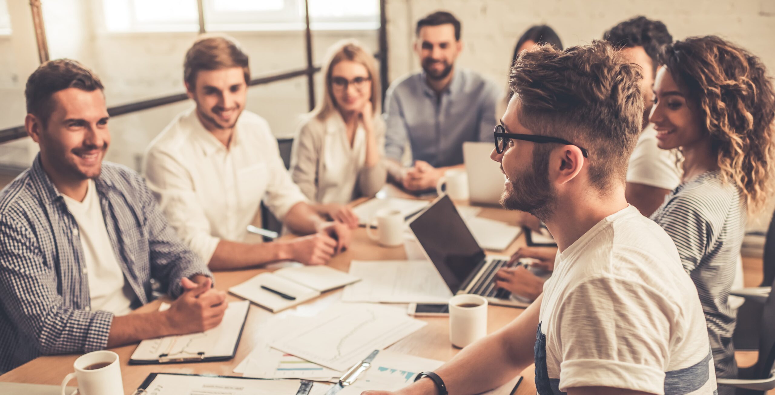 Un grup de joves professionals discutint idees en una reunió de treball col·laborativa.