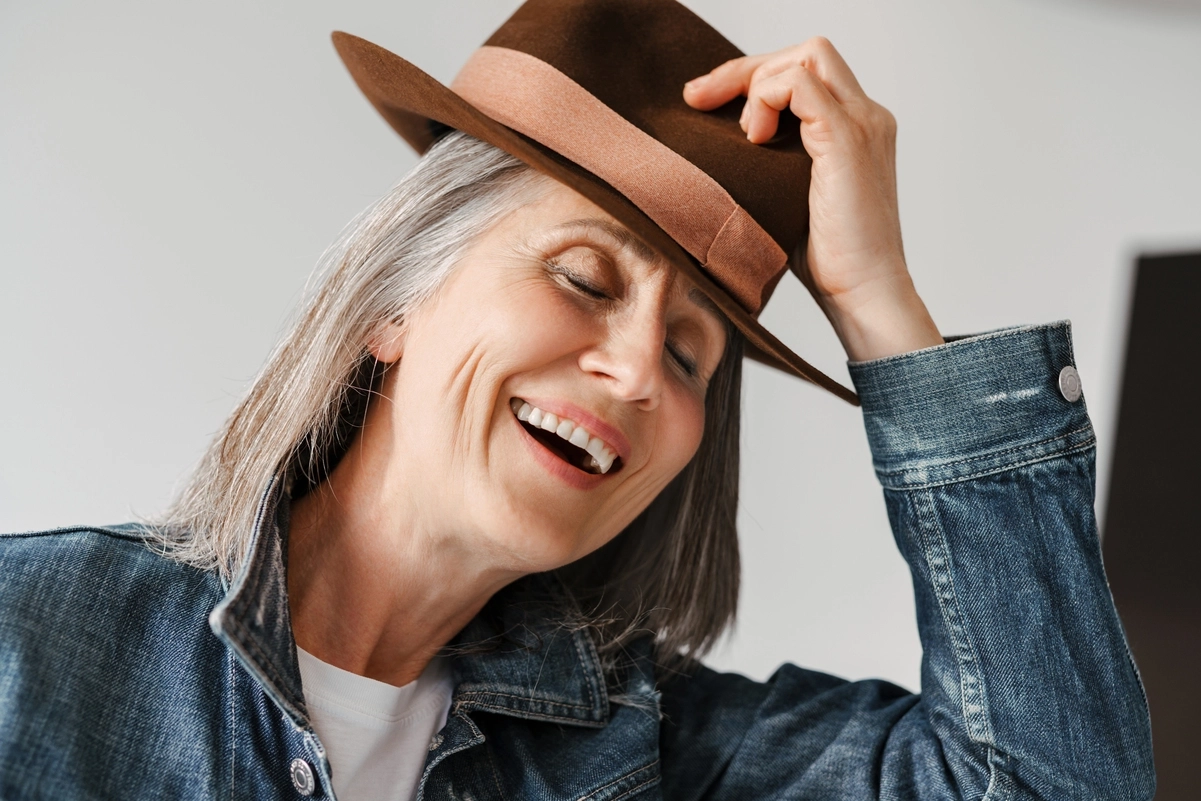Mujer mayor sonriendo con un sombrero, representando la jubilación especial a los 64 años.