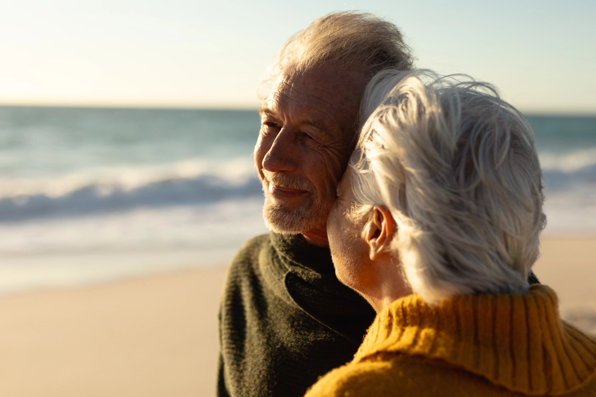 Pareja de jubilados en la playa al atardecer, representando los viajes baratos del Imserso.
