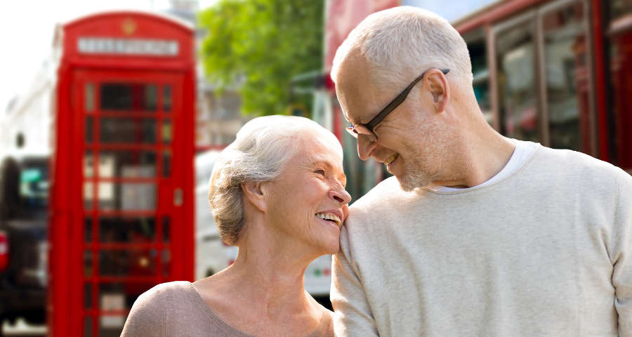 Parella de jubilats somrients explorant el sistema de pensions britànic en el seu viatge.