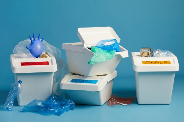 Cubos de reciclaje con residuos clasificados, representando la reducción de la huella de carbono.