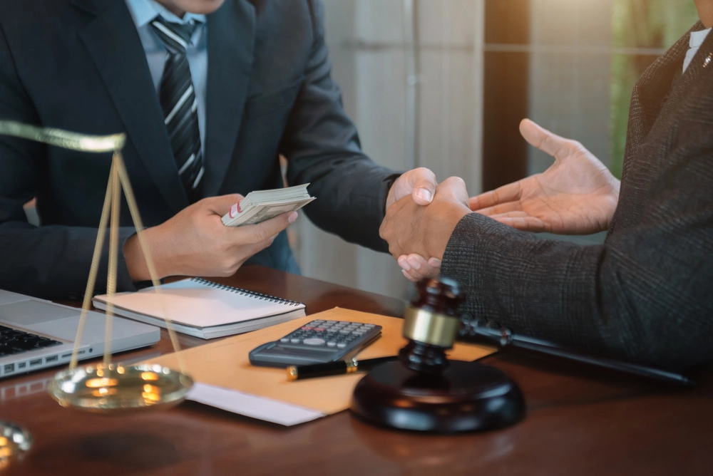 Dos personas en oficina con dinero, simbolizando la paga extra de funcionarios y su cálculo.
