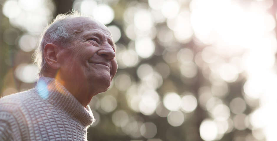 Hombre mayor sonriente mirando al horizonte, representando tranquilidad con pensión no contributiva.