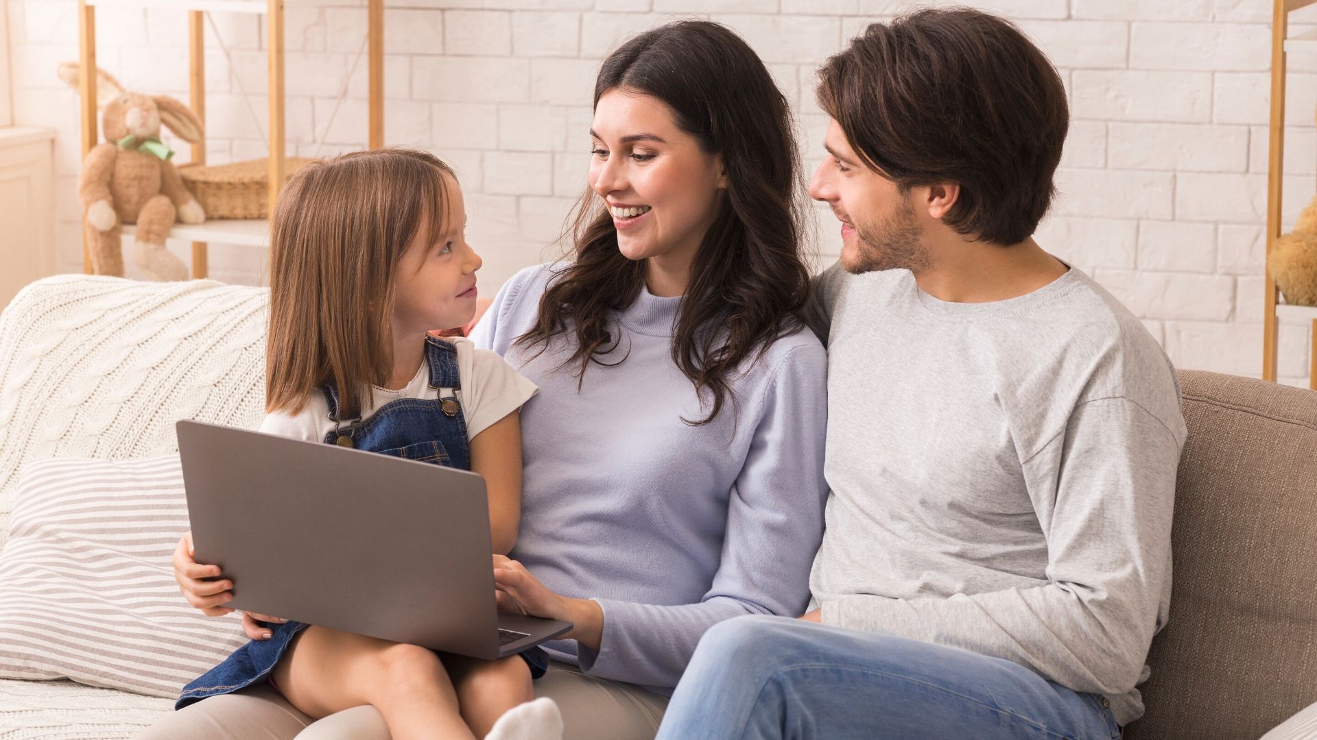 Familia reunida en el sofá planificando juntos su economía doméstica con un portátil.