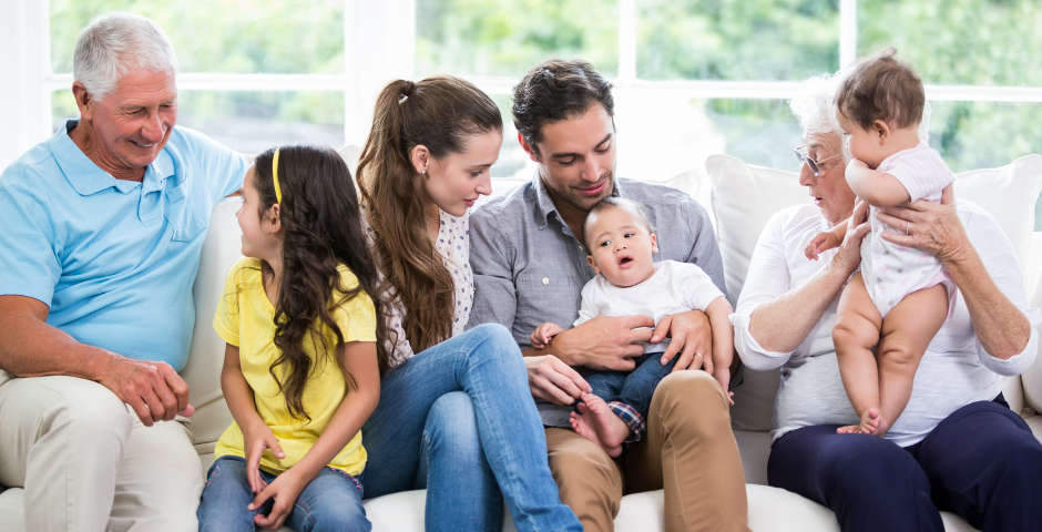 Familia reunida en un sofá disfrutando de un momento juntos, reflejando el ahorro al hacer testamento.