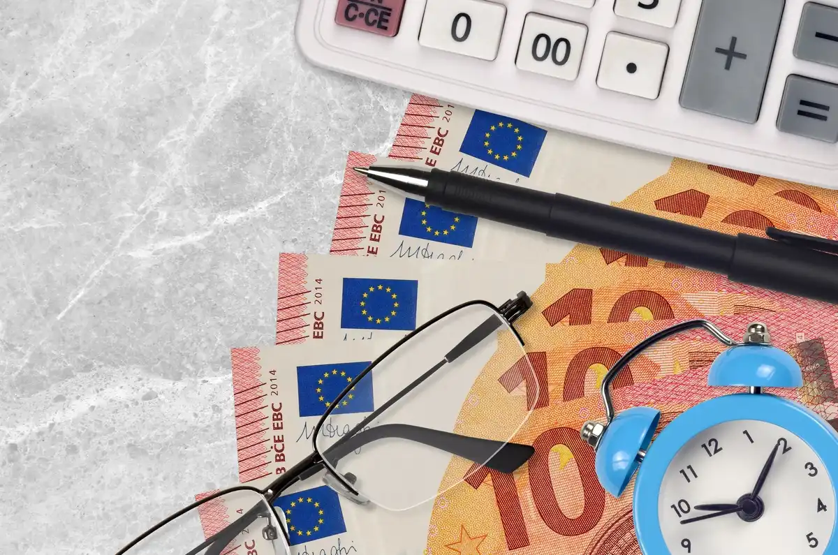 Bitllets de 100 euros, calculadora i rellotge, simbolitzant estalvi programat.