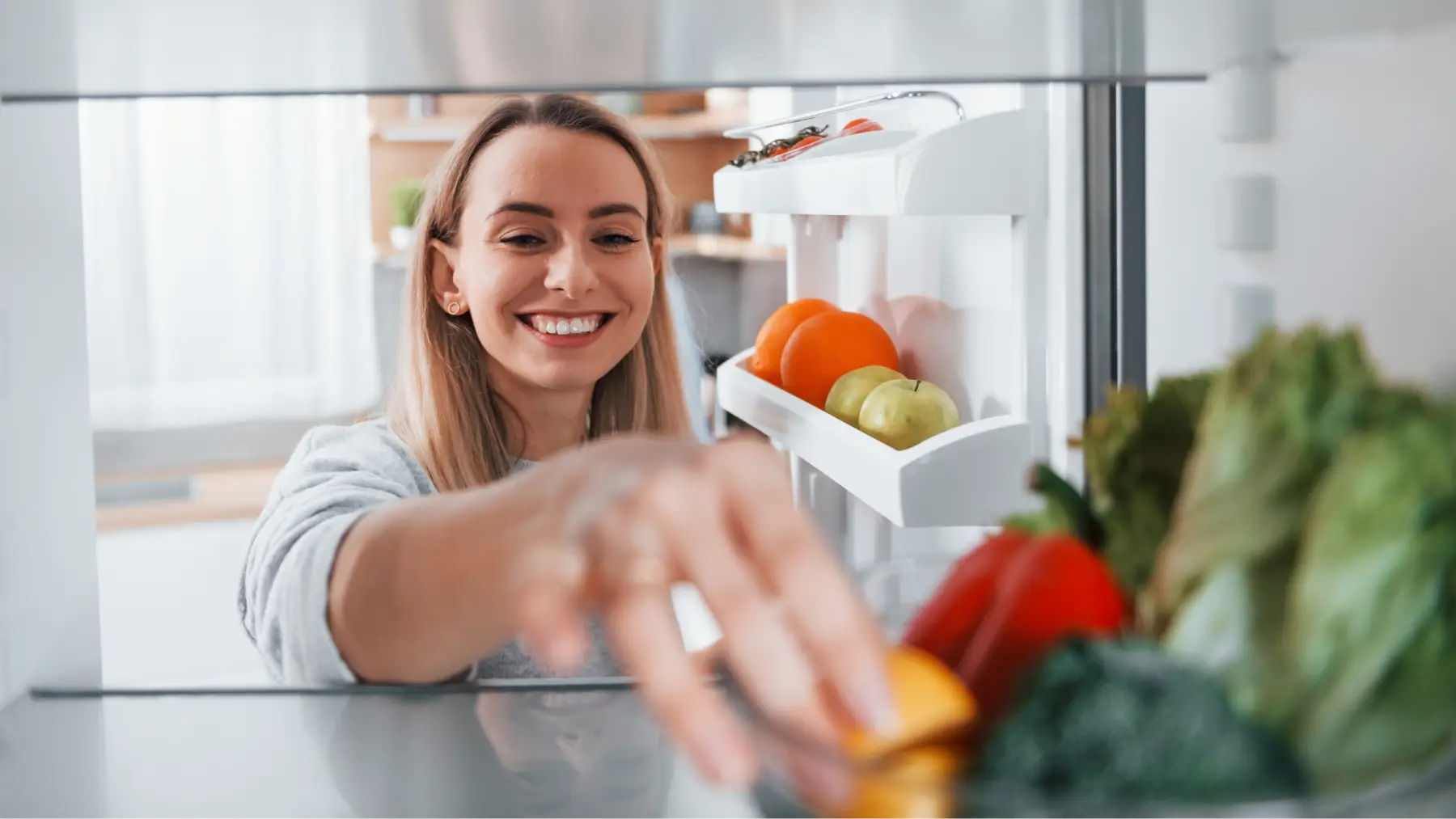 Mujer organizando alimentos en la nevera, aplicando consejos para ahorrar energía.