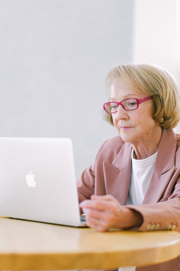 Mujer mayor con gafas consultando su plan de pensiones en un ordenador.