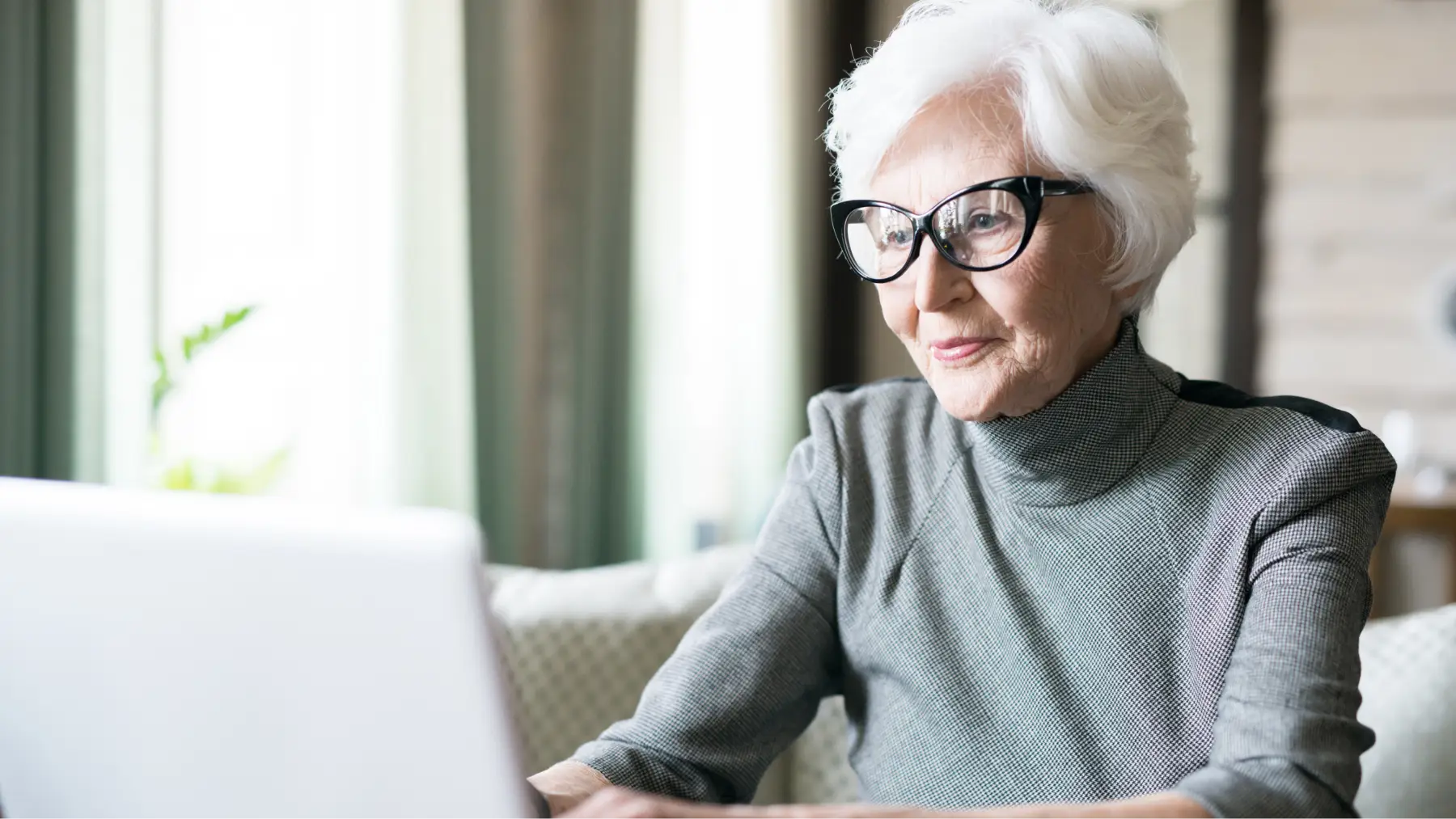 Mujer mayor con gafas consultando su plan de pensiones en un ordenador.