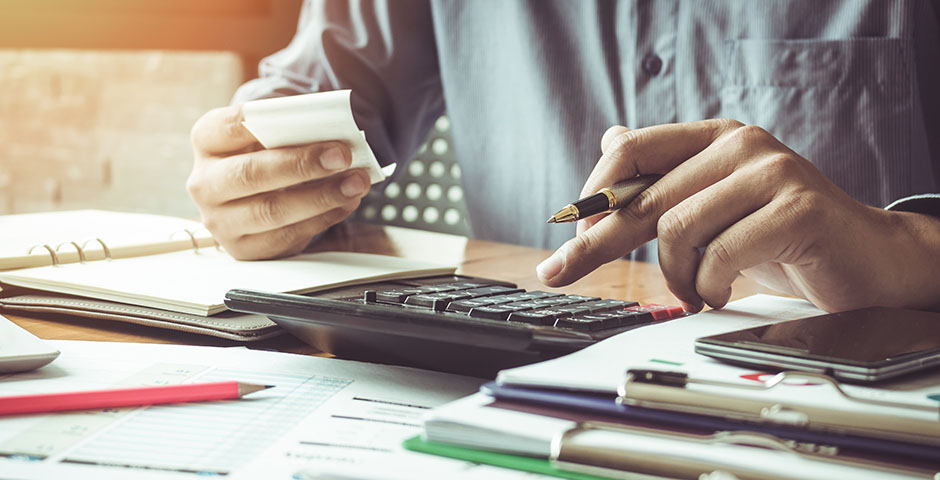 Persona utilitzant calculadora i revisant documents sobre bases reguladores i de cotització.