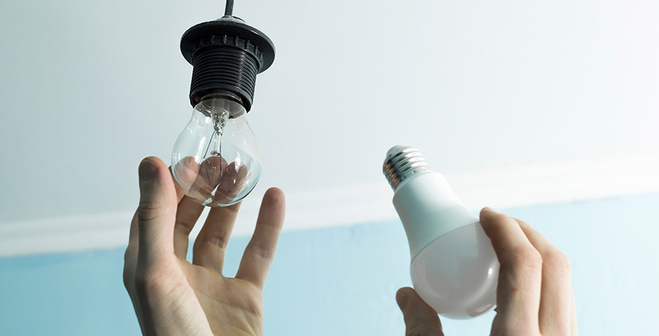 Mans canviant una bombeta tradicional per una LED per fomentar lestalvi denergia.