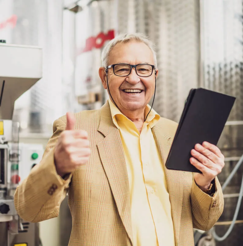 Emprendedor senior sonriendo con una tablet en una fábrica.