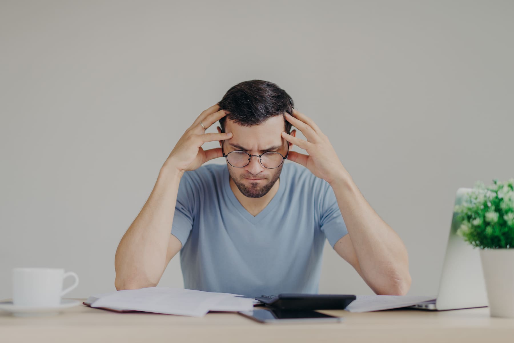 Hombre preocupado revisando cálculos sobre el interés compuesto en su escritorio.