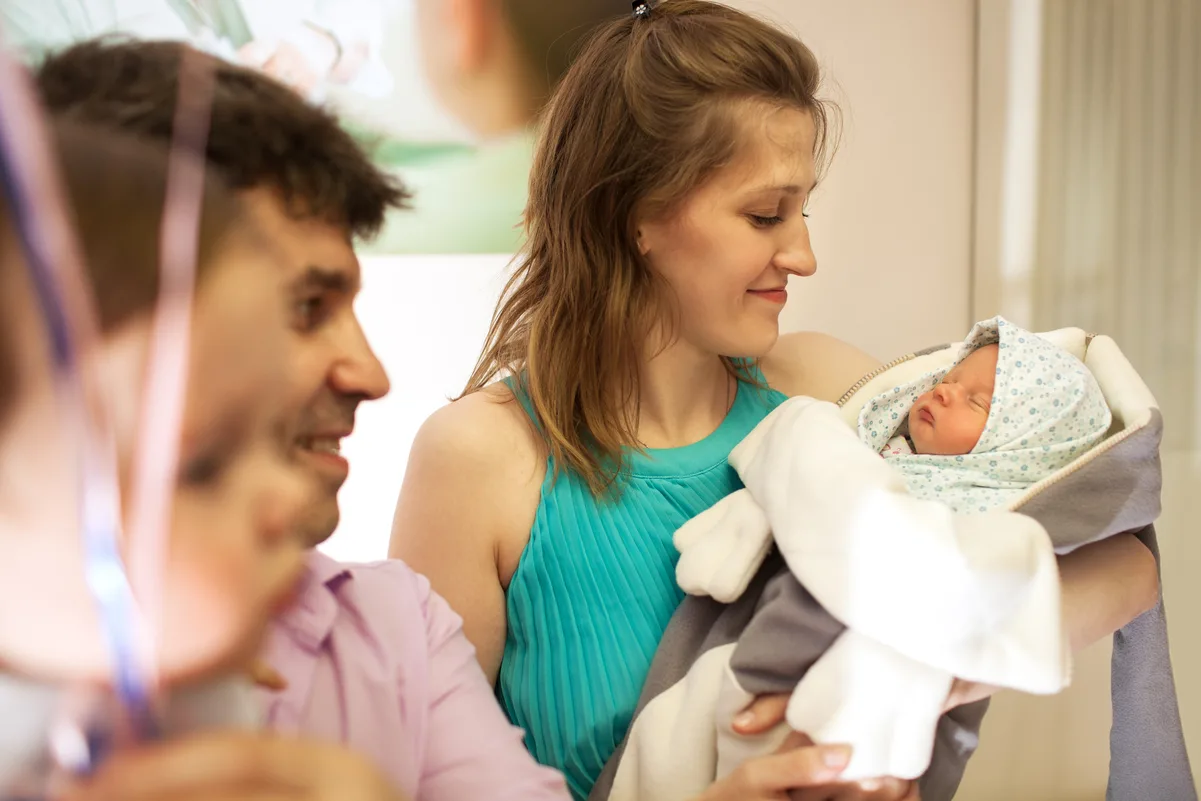 Pareja sonriente con recién nacido, simbolizando el proceso de solicitud de prestación por maternidad y paternidad.