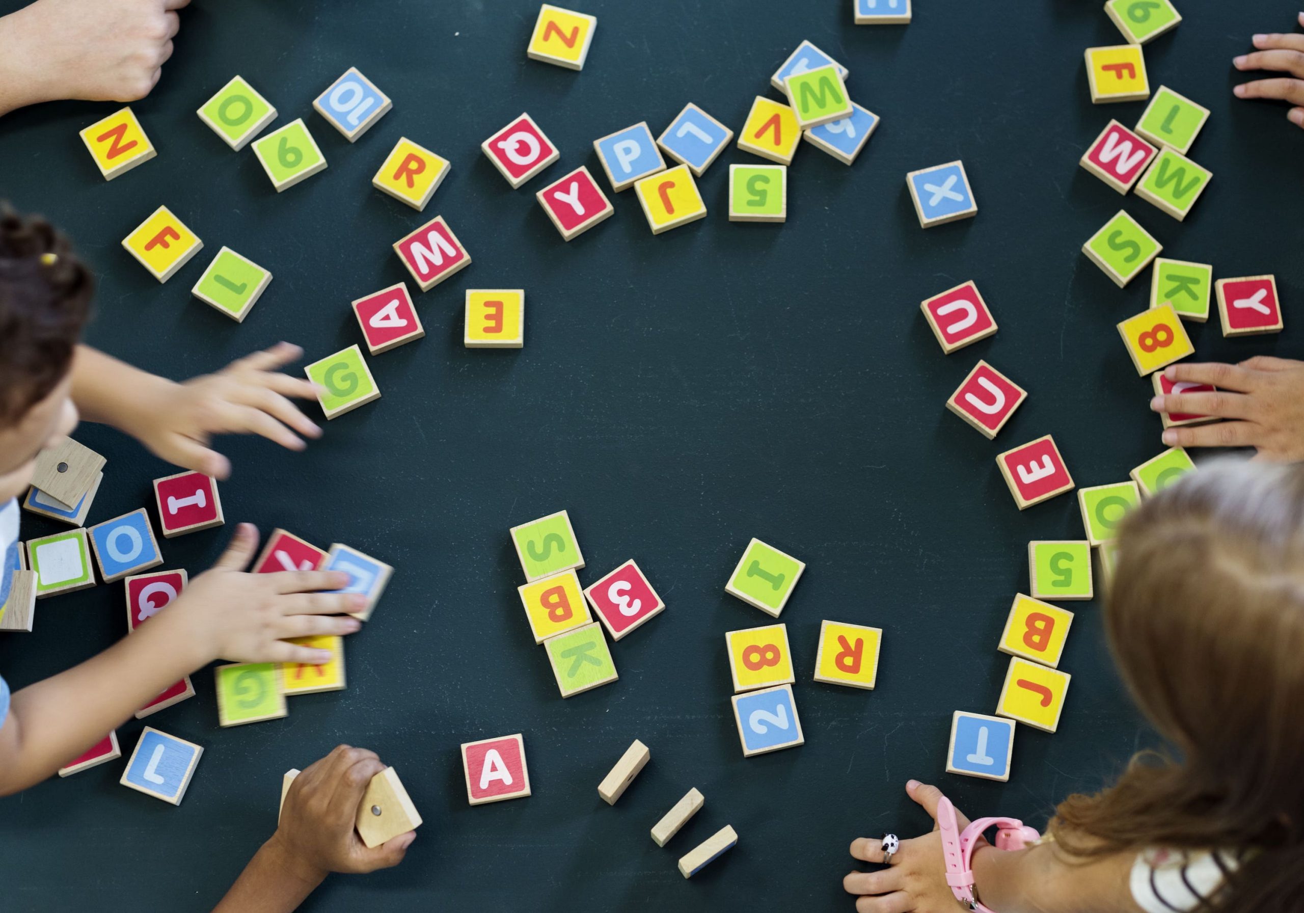 Niños jugando con bloques de letras y números, representando conceptos clave del ahorro.