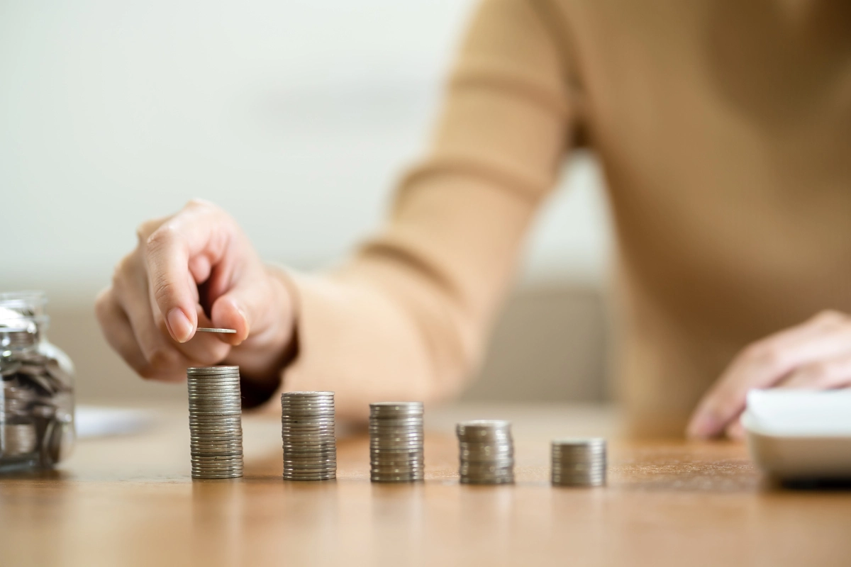 Mano repartiendo monedas entre bloques, ilustrando donaciones y desgravación fiscal.