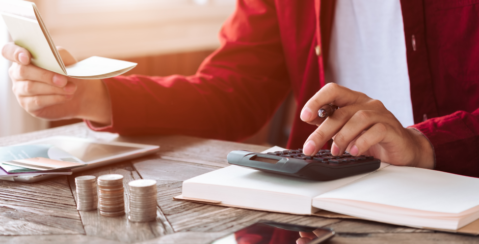 Persona calculando su renta con calculadora, libreta y documentos en la mesa.