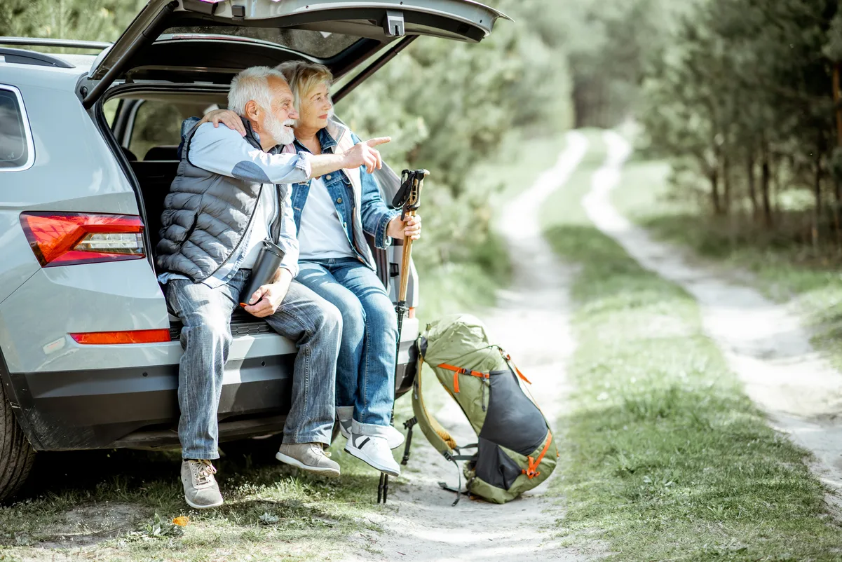 Pareja de jubilados caminando en la naturaleza, disfrutando de descuentos exclusivos para pensionistas.