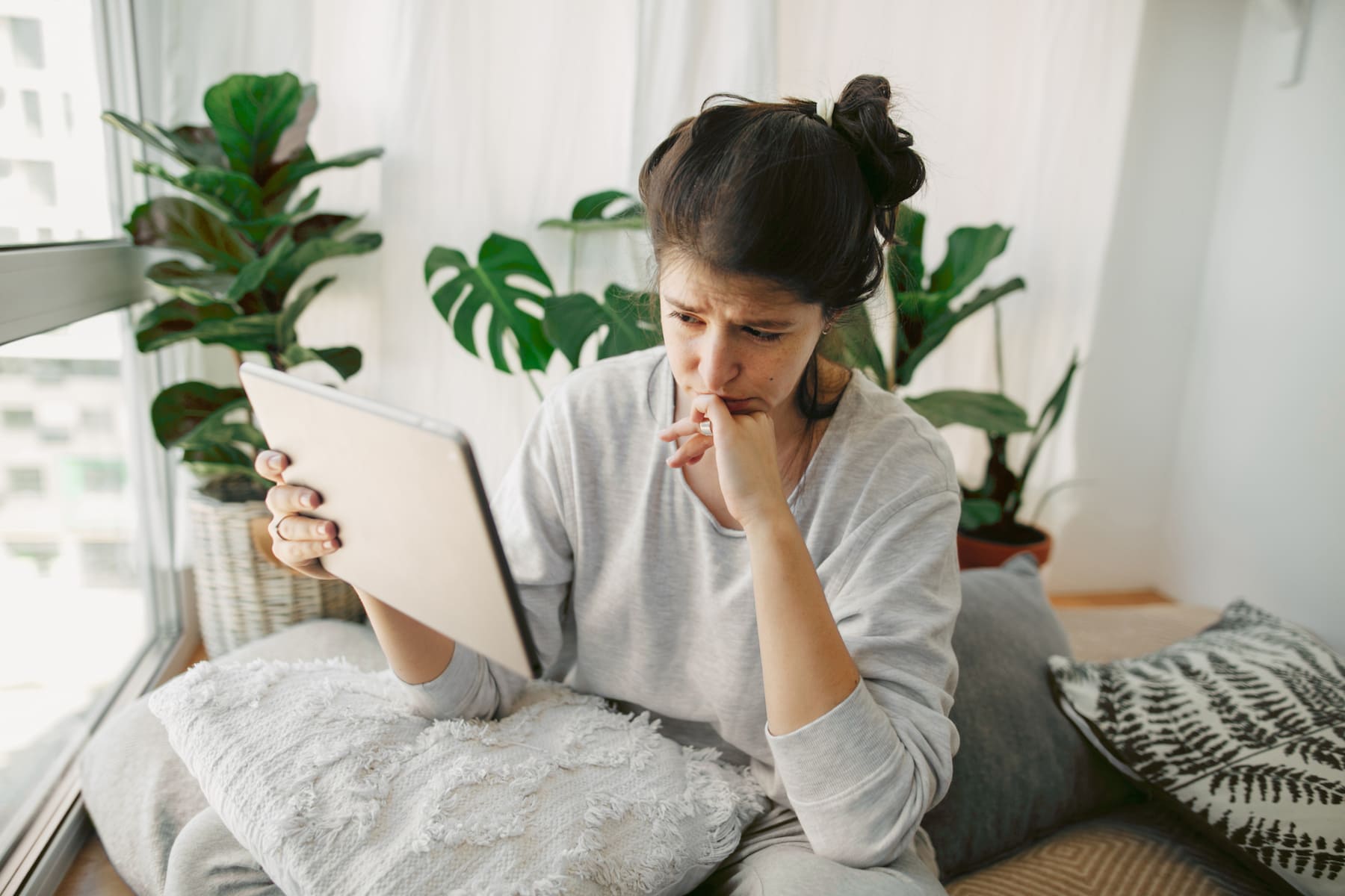 Dona preocupada revisant informació a la tablet, simbolitzant l'atur per a treballadors autònoms.