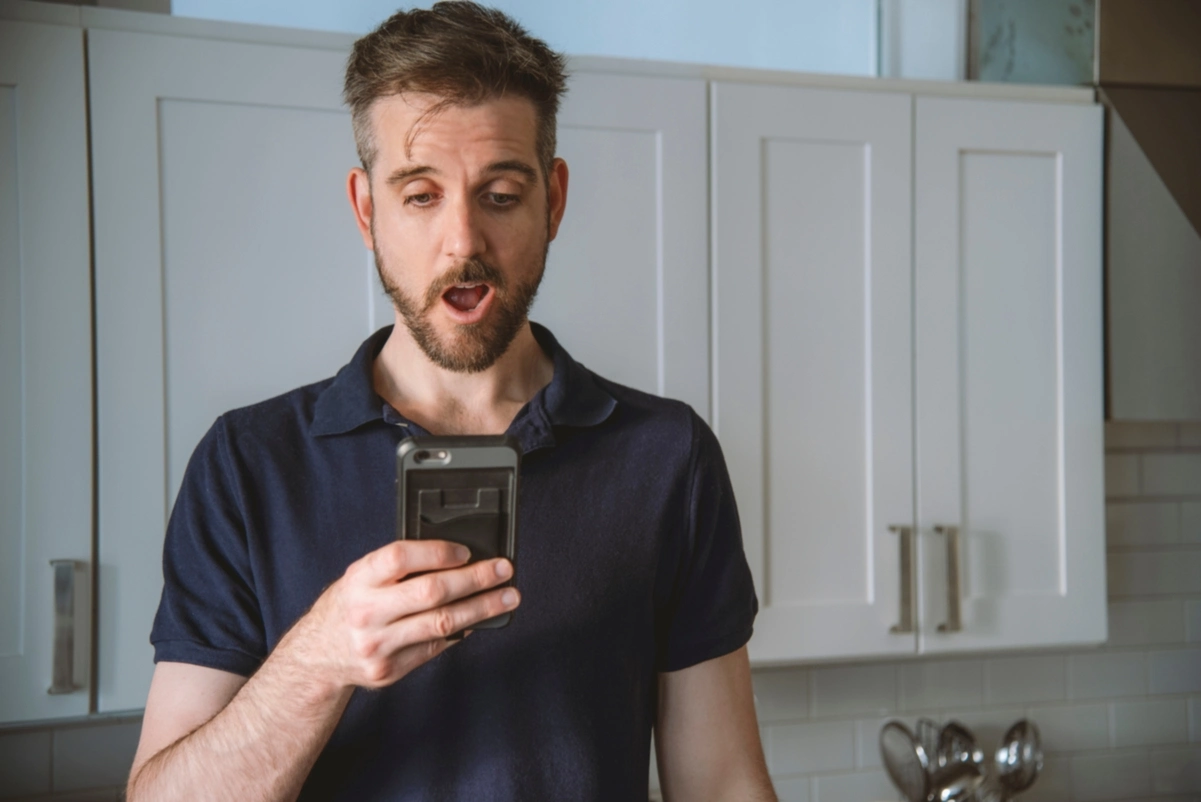 Hombre sorprendido mirando el teléfono, simbolizando la incertidumbre ante un posible despido durante una baja.