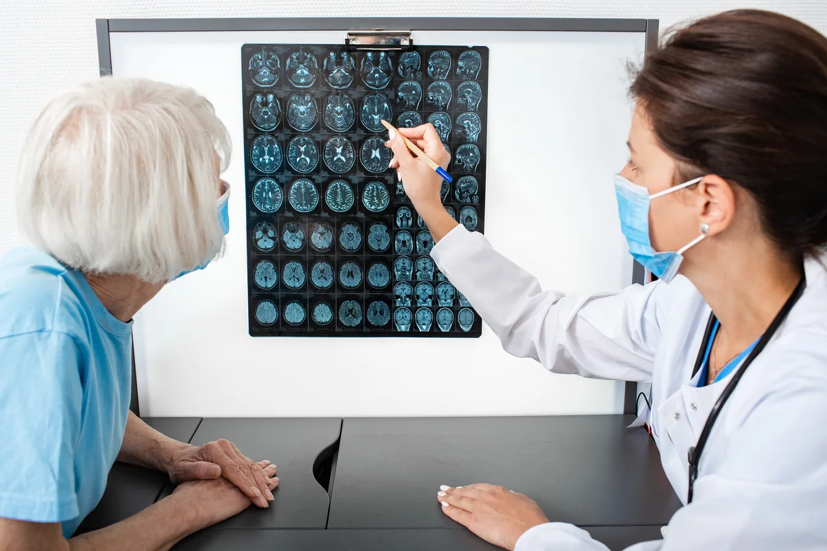 Doctora explica ressonància magnètica a pacient gran per detectar Alzheimer.