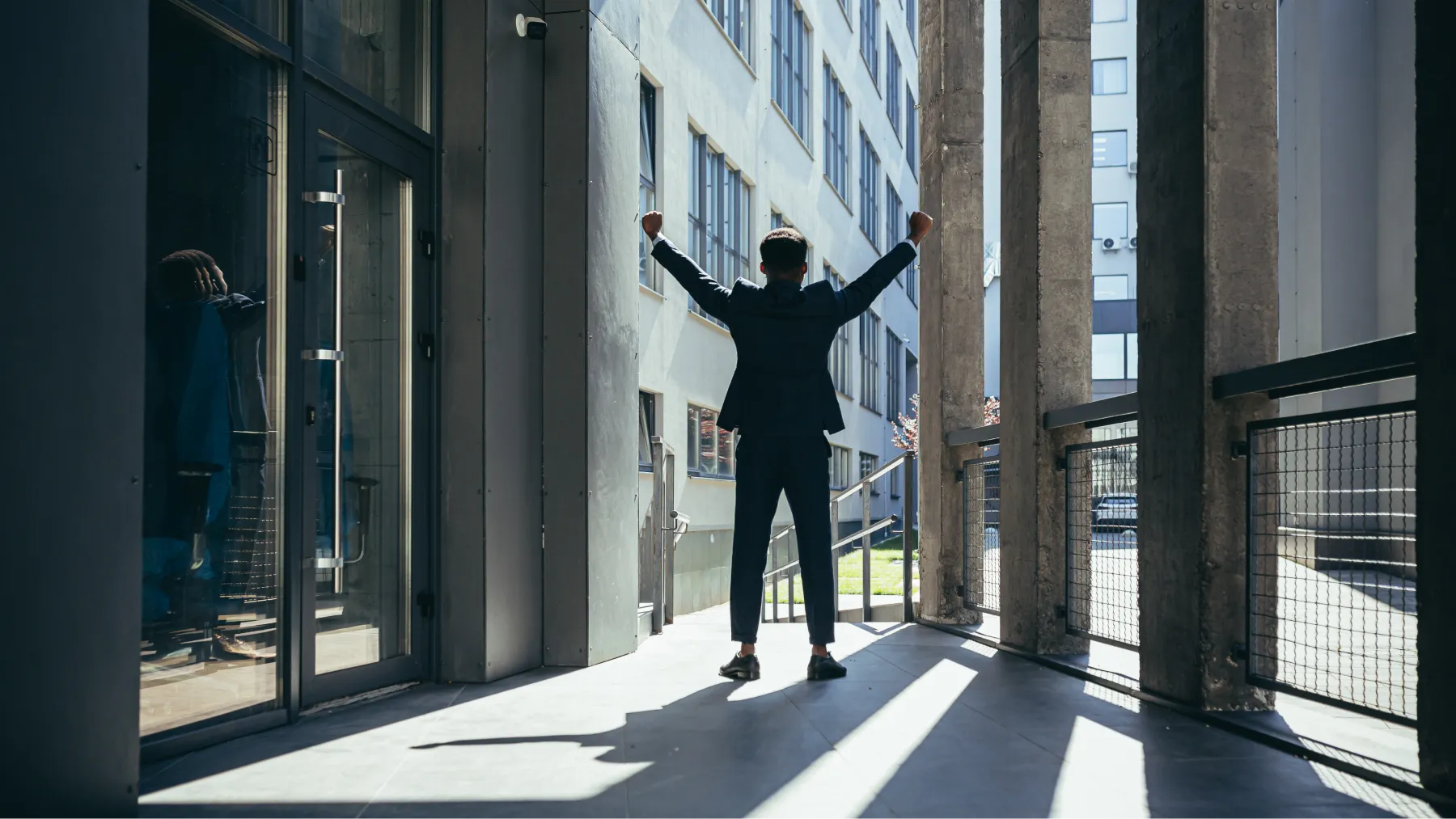 Hombre saliendo de un edificio con brazos en alto, representando el día exacto de su jubilación.