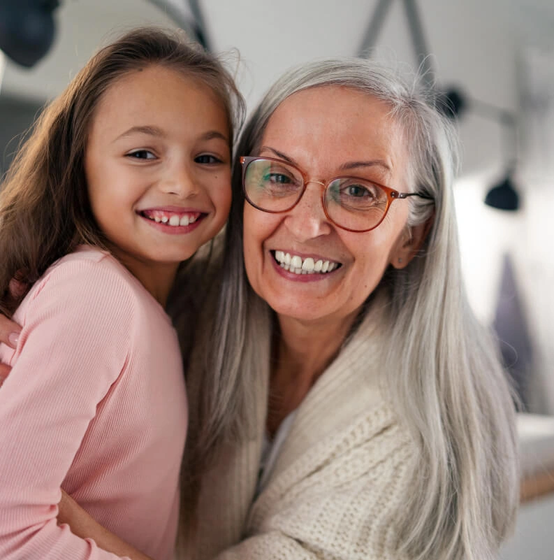 Abuela y nieta sonriendo abrazadas, reflejando el concepto de herencia y legado familiar.