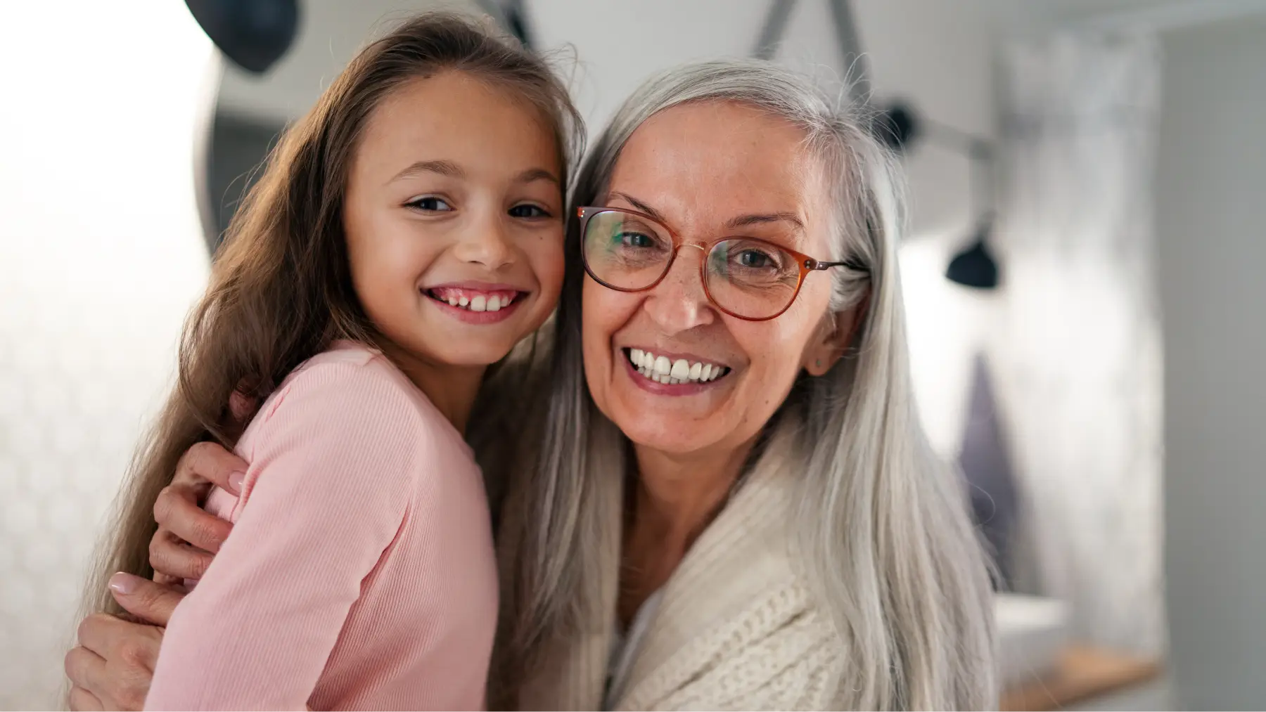 Abuela y nieta sonriendo abrazadas, reflejando el concepto de herencia y legado familiar.