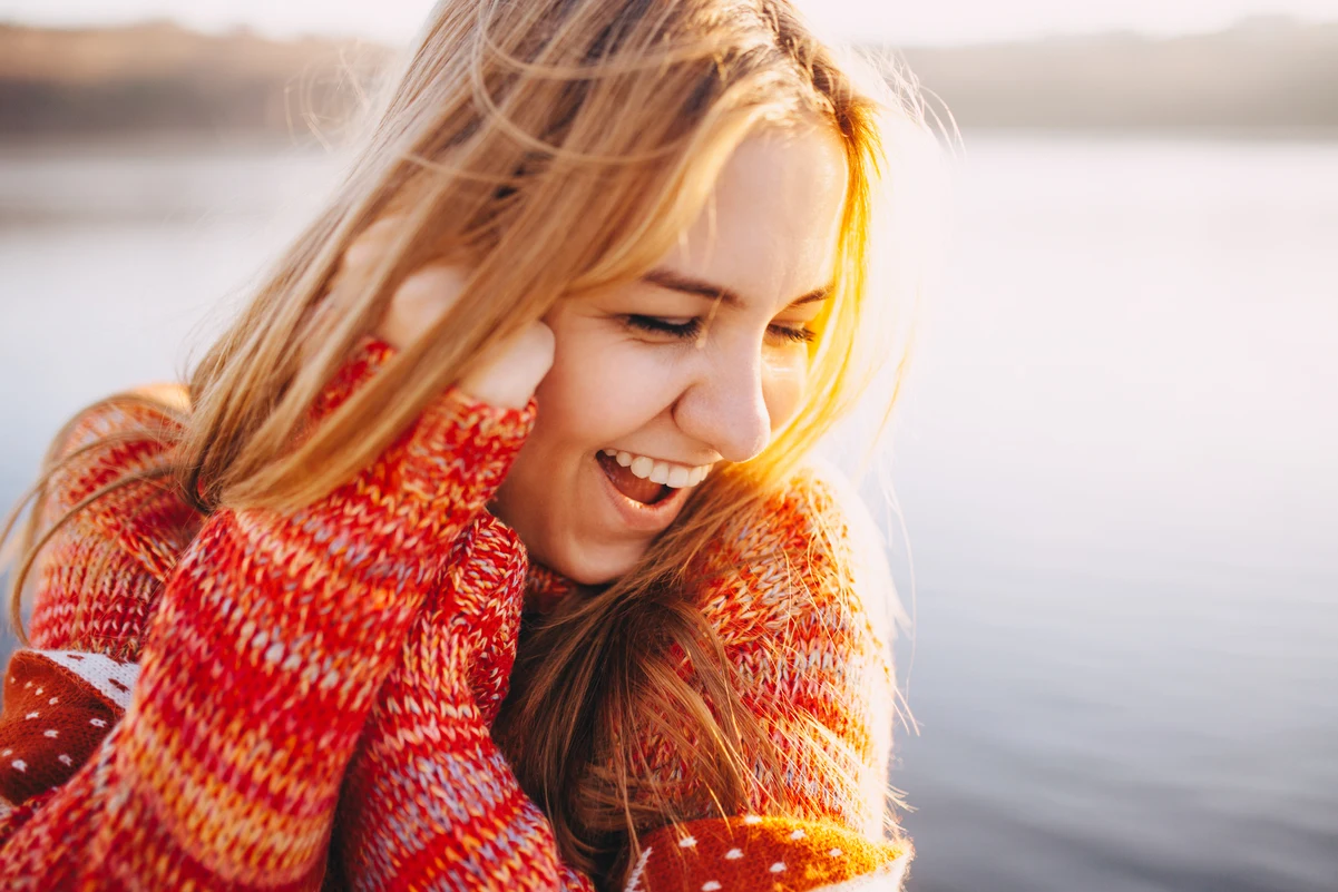 Mujer sonriente al aire libre, simbolizando la economía de la felicidad y su impacto en el bienestar.