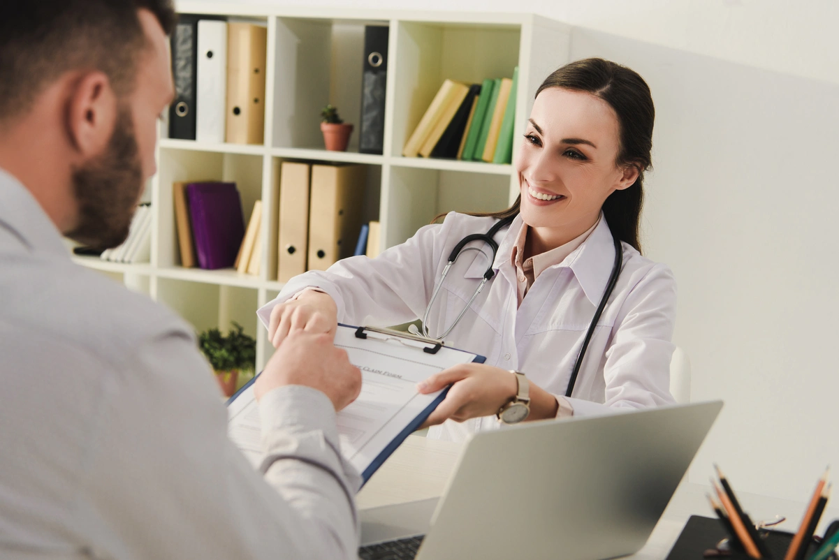Médico entregando documentos a un hombre, ilustrando la importancia de la edad actuarial en seguros de vida.