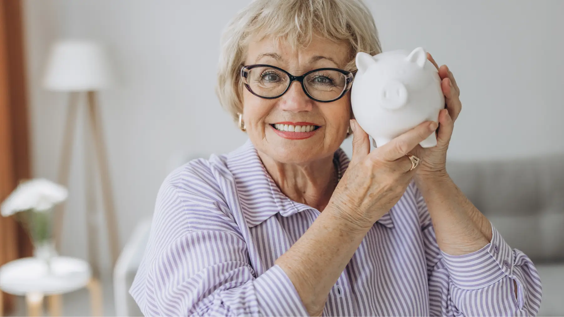 Mujer mayor sonriente sosteniendo una hucha, simbolizando la elección del mejor plan de pensiones.