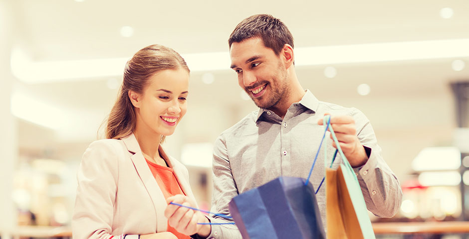 Pareja sonriendo mientras revisan bolsas de compras, simbolizando el control de compras impulsivas.