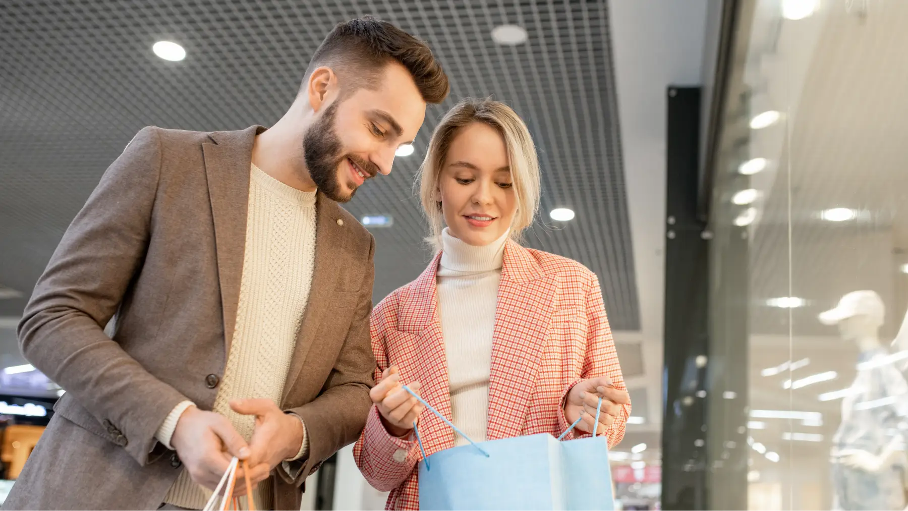 Pareja sonriendo mientras revisan bolsas de compras, simbolizando el control de compras impulsivas.