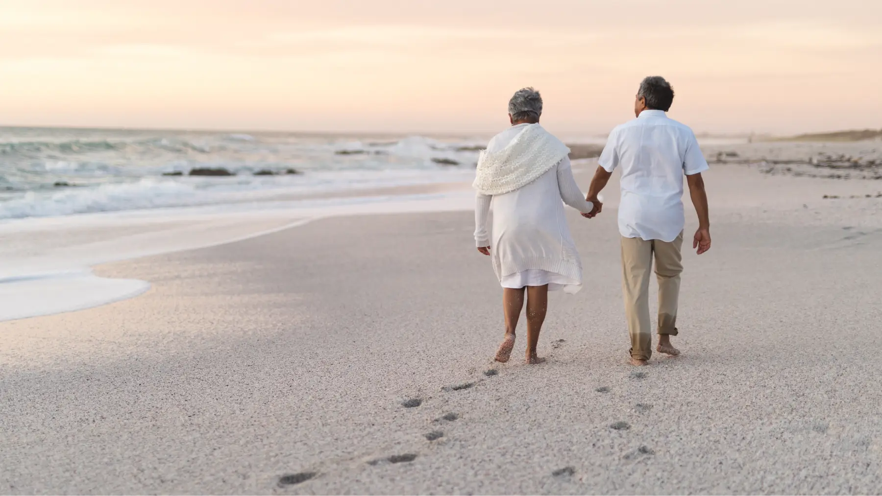 Pareja de jubilados caminando por la playa, simbolizando el impacto de una excedencia en la pensión.