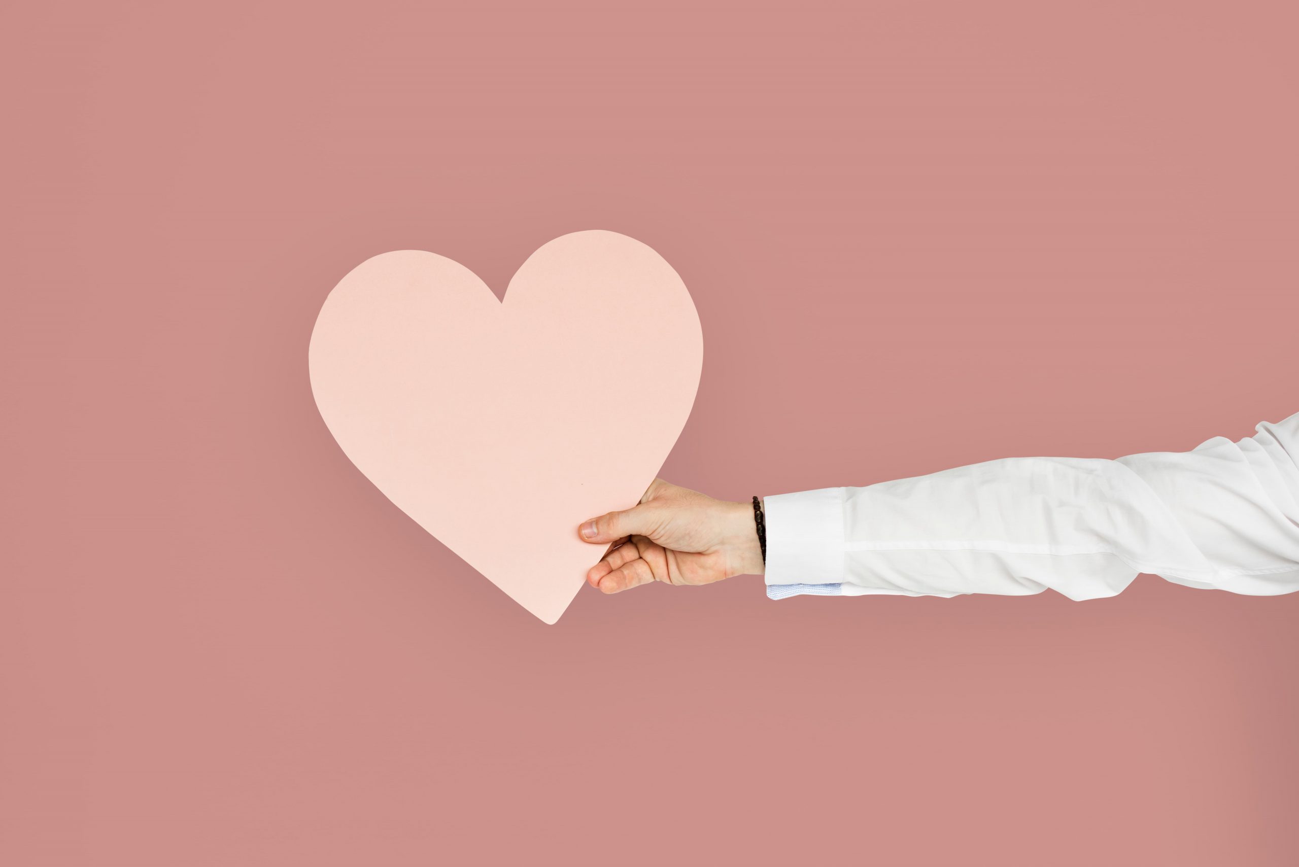 Mano sosteniendo un corazón rosa simbolizando cuidado familiar y planificación futura.