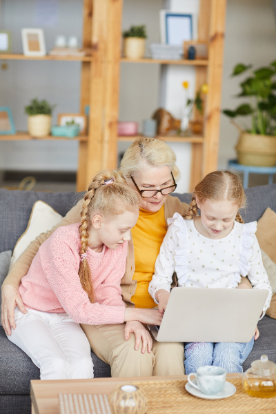 Abuela con sus nietas revisa información sobre herederos legales en un portátil.
