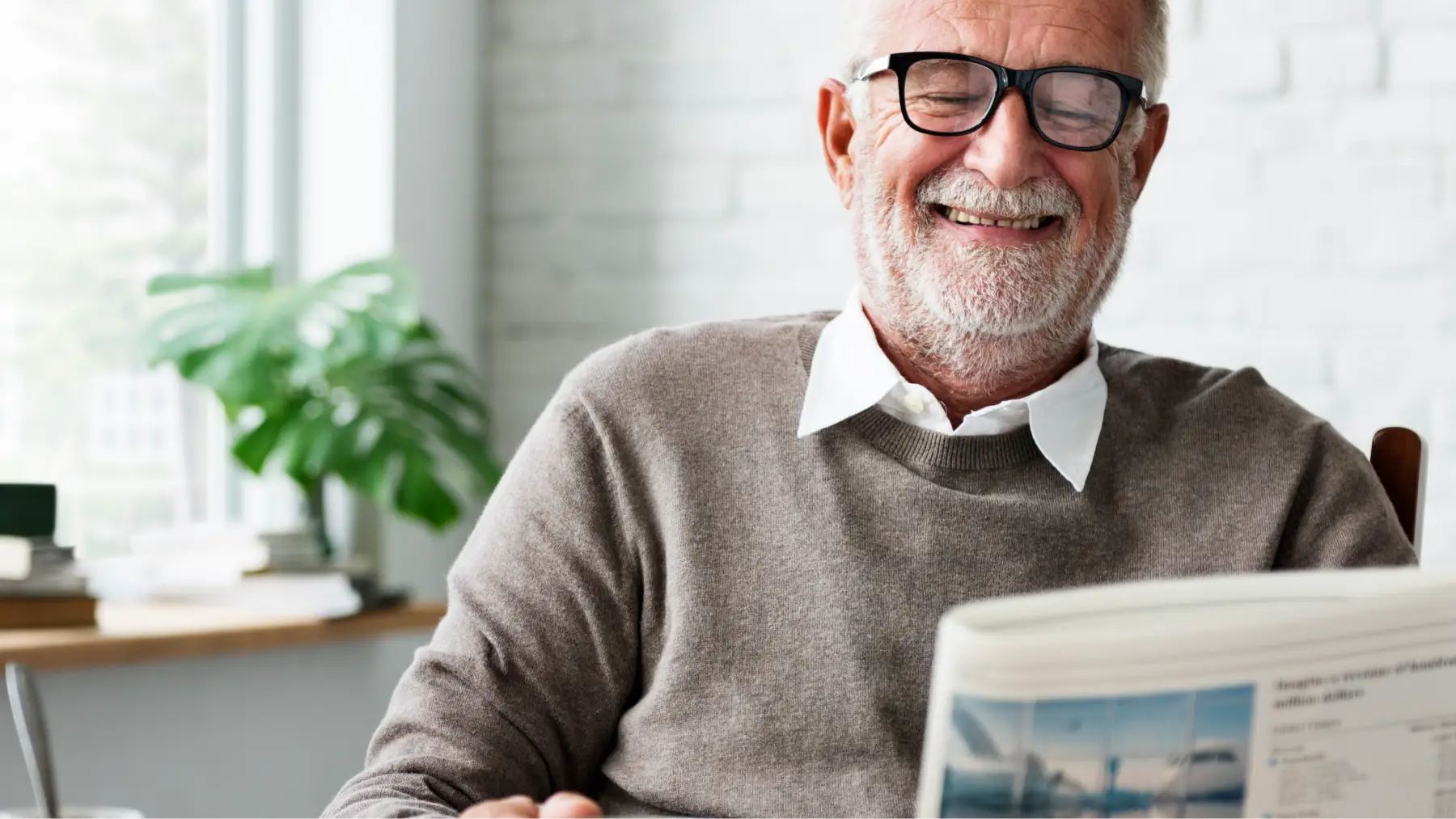 Hombre mayor sonriente leyendo el periódico mientras disfruta de su jubilación parcial.