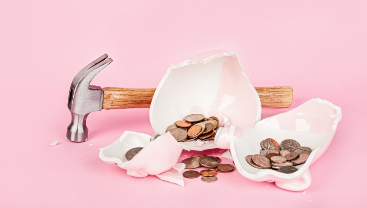 Hucha rota con monedas y martillo, simbolizando el estado actual de las pensiones.
