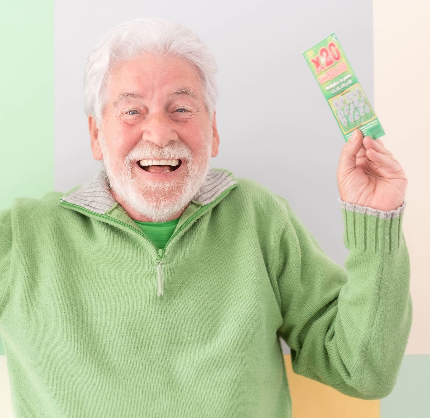Hombre mayor sonriente con un boleto de lotería ganador en la mano.