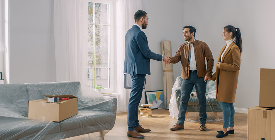 Pareja estrechando la mano de un agente en una vivienda, representando la venta de una propiedad heredada.