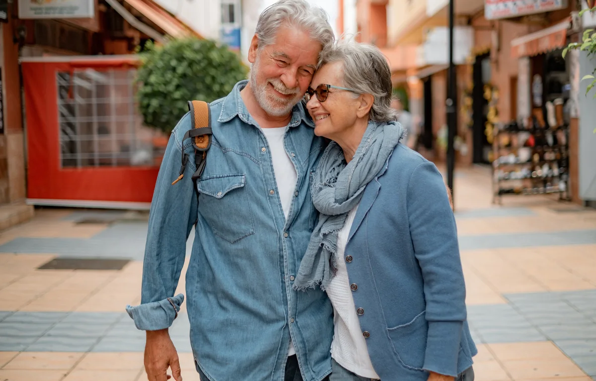 Pareja jubilada abrazándose sonriente en la calle, disfrutando de la jubilación como fijos discontinuos.