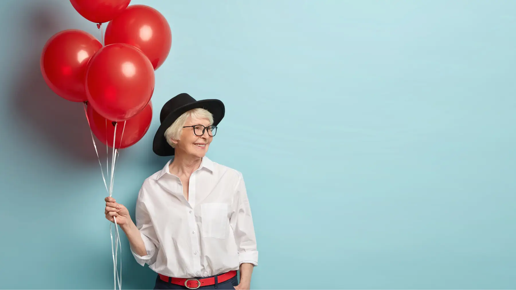 Mujer mayor sonriente con globos rojos, representando la posibilidad de jubilarse a los 60 años. 
