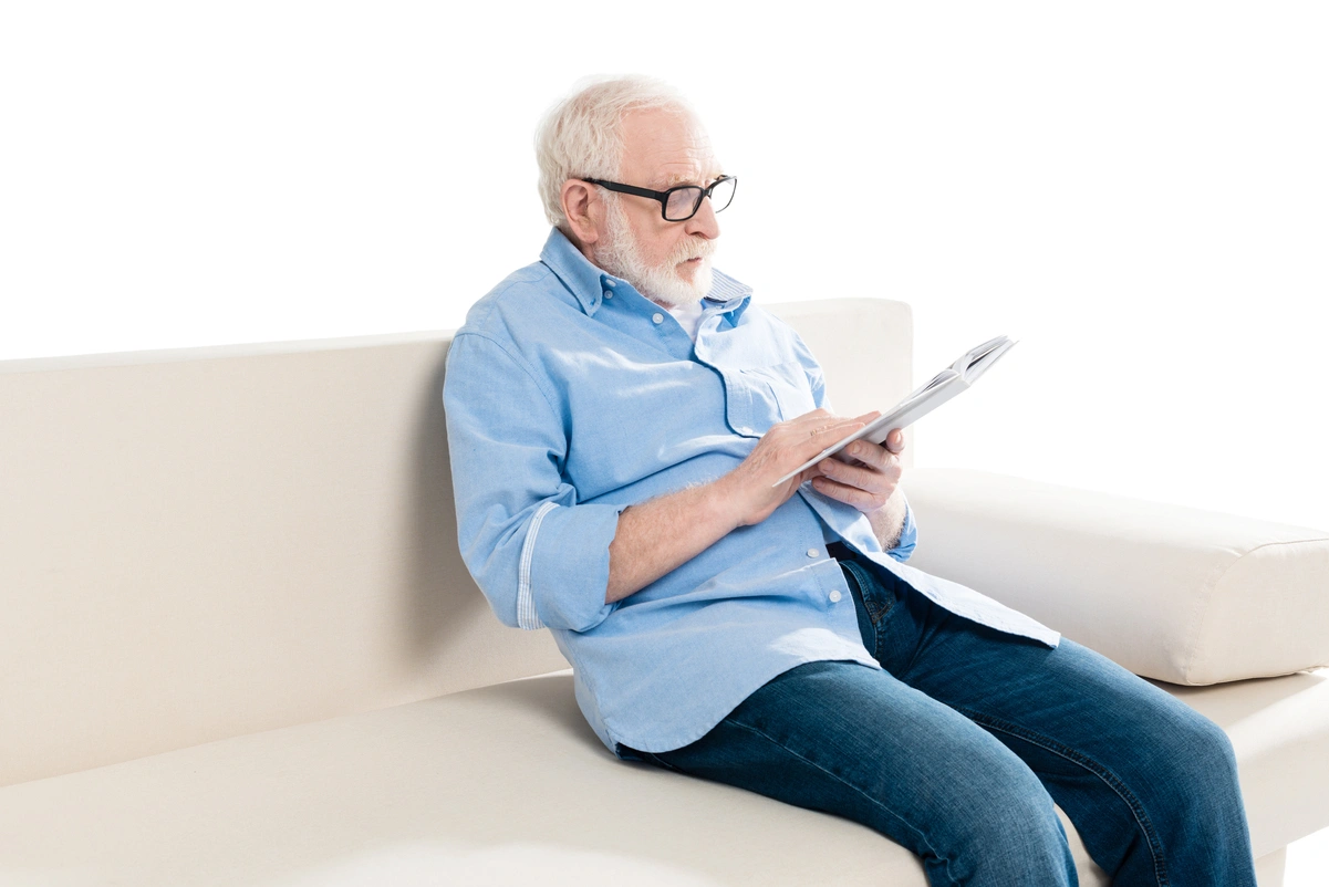 Hombre mayor en sofá leyendo un libro, representando recomendaciones esenciales sobre la jubilación.