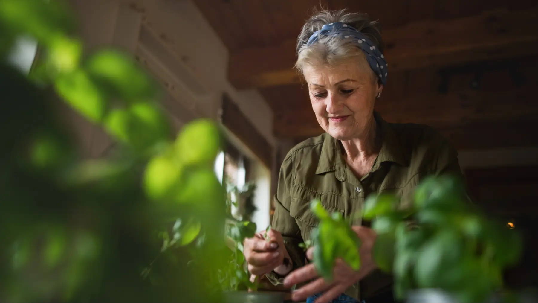 Mujer mayor sonriendo mientras cuida plantas, destacando cosas que mejoran con la edad.