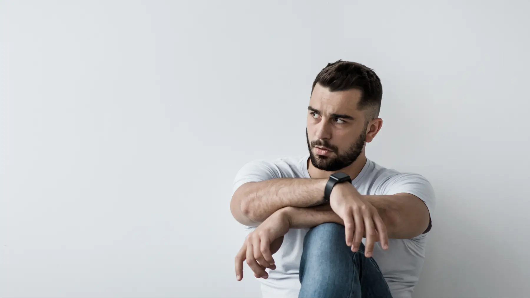Home preocupat assegut a terra, simbolitzant la importància de contractar una assegurança de vida.