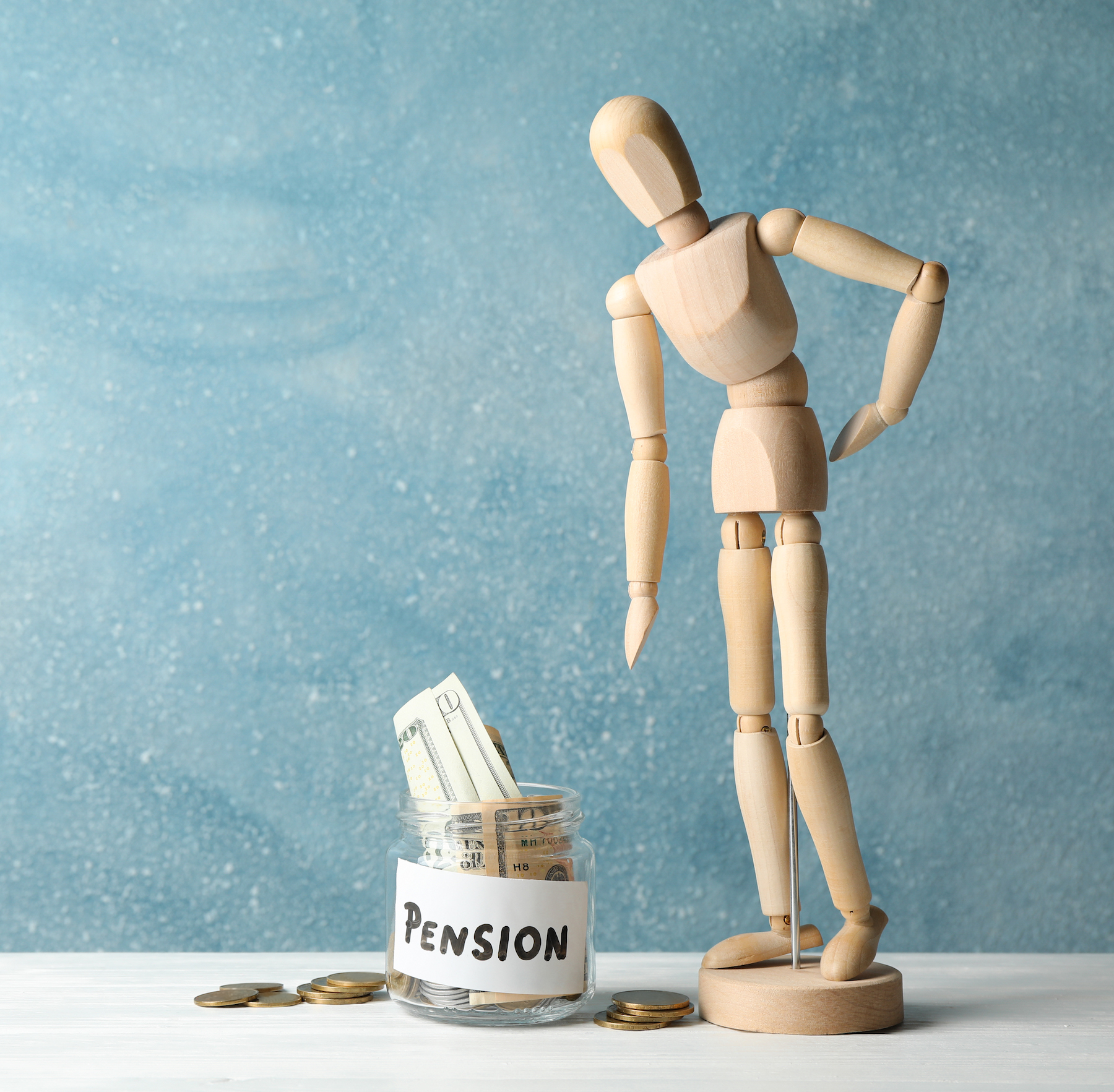 Figura de fusta al costat de flascó amb diners, representant nous fons de pensions públics per a autònoms.