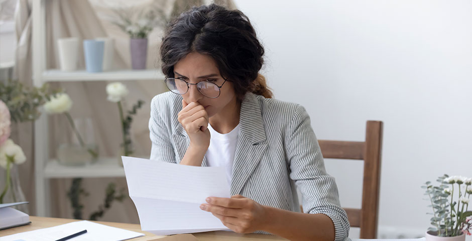 Mujer preocupada revisando documentos, simbolizando el olvido de sellar el paro y sus implicaciones.