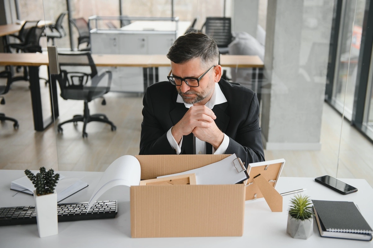 Hombre mayor revisando caja en oficina, simbolizando la búsqueda de empleo tras los 55 años.