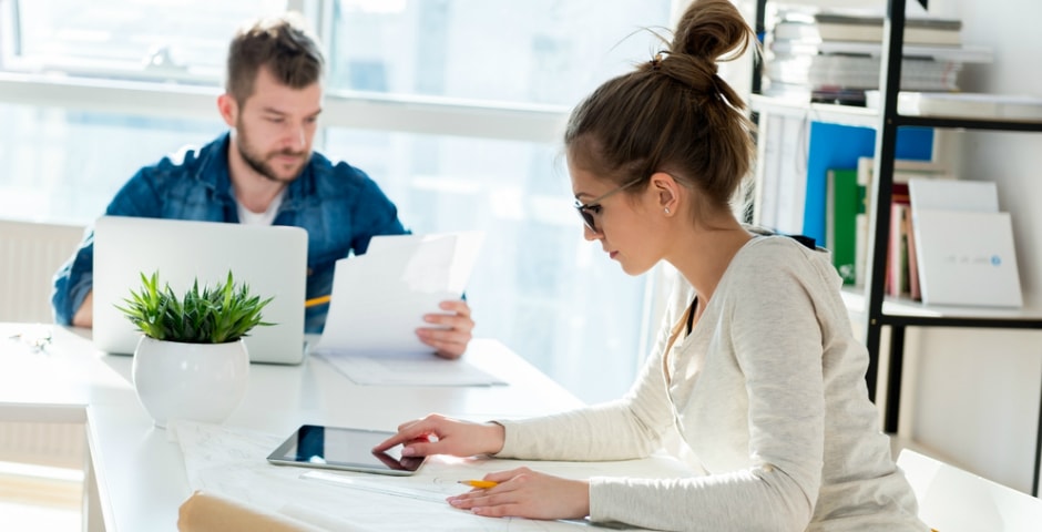 Pareja organizando facturas y tomando notas, aplicando trucos para ahorrar dinero día a día.